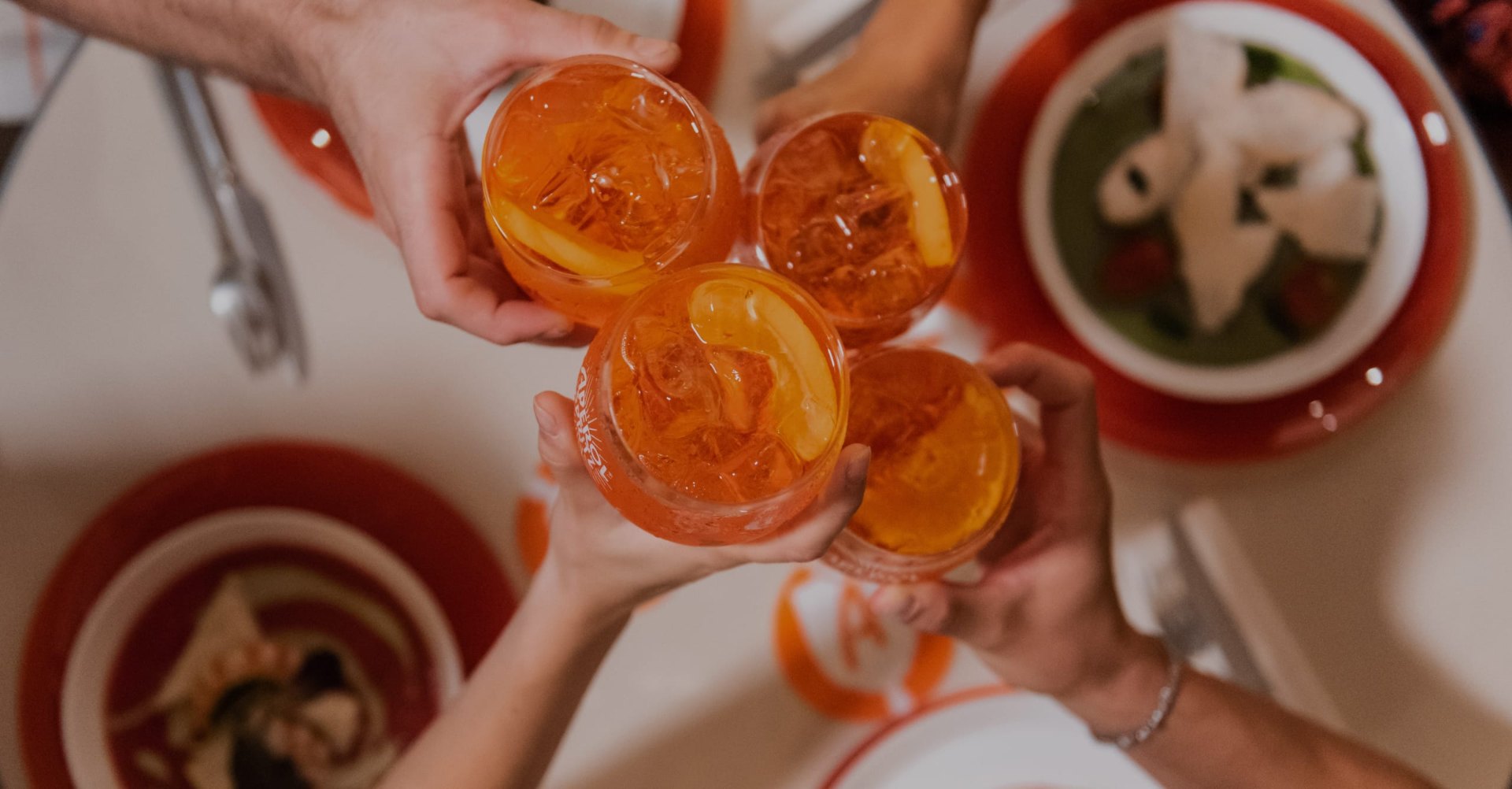 Sticlă de Aperol și pahare de spritz pe bar, la lumina apusului